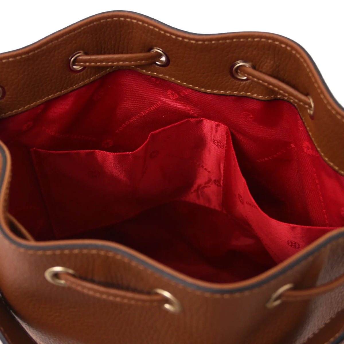 Close-up of a brown leather bucket bag showing the red satin-lined interior with drawstring closure and metal eyelets.