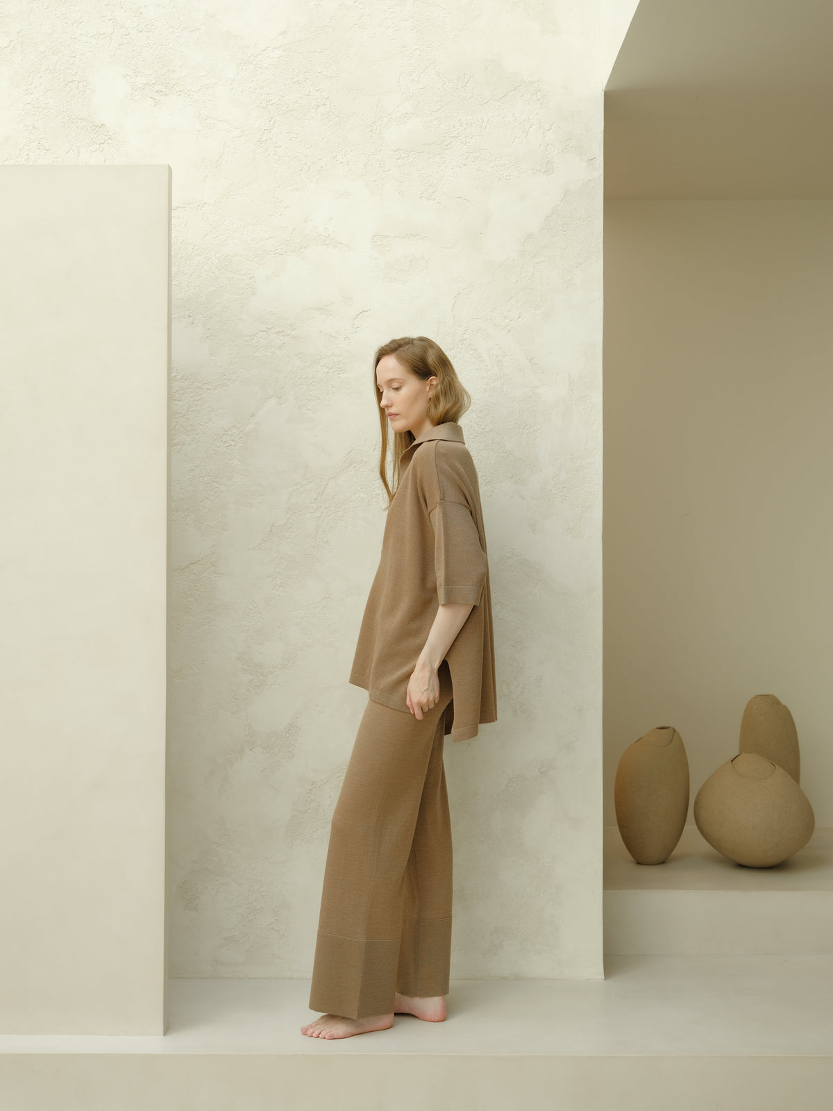 Side view of a model in taupe Maxi polo de lana merina extrafina set, loose top with three-quarter sleeves and matching wide pants.