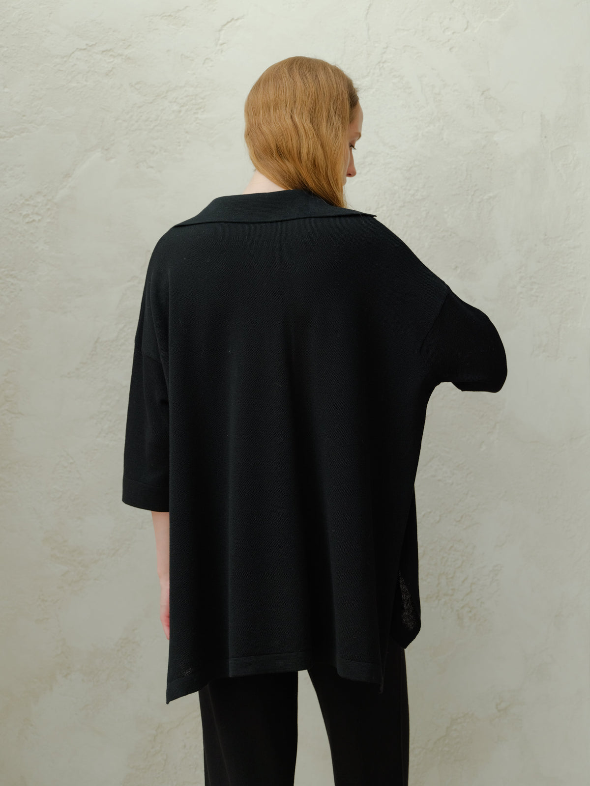 Back view of a modelo con a black Maxi polo de lana merina extrafina with a corte relajado.
