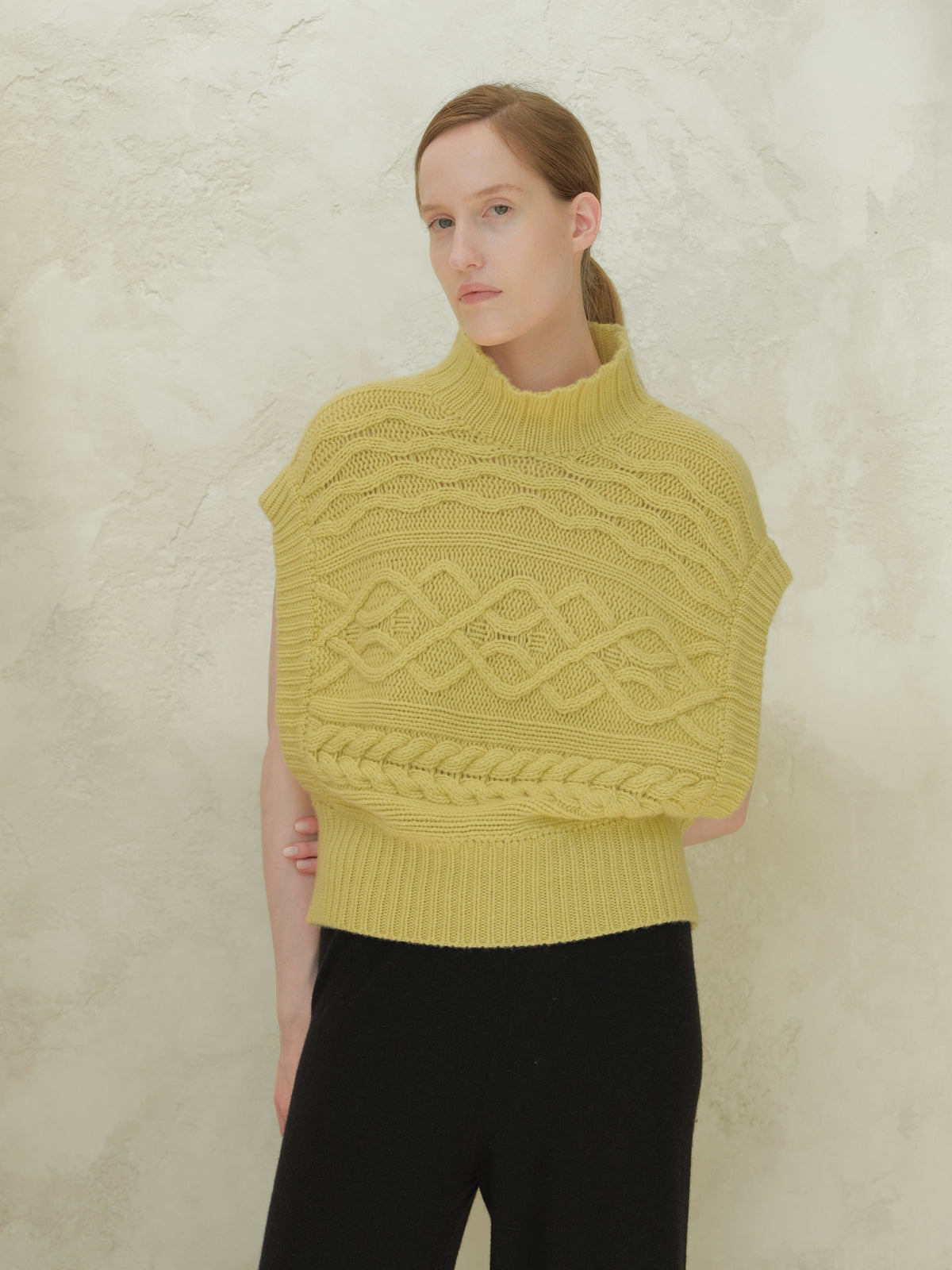 Front view of a Model trägt a yellow cashmere mix Maxi-Zopfstricktunika with a high ribbed collar and bold cable patterns.