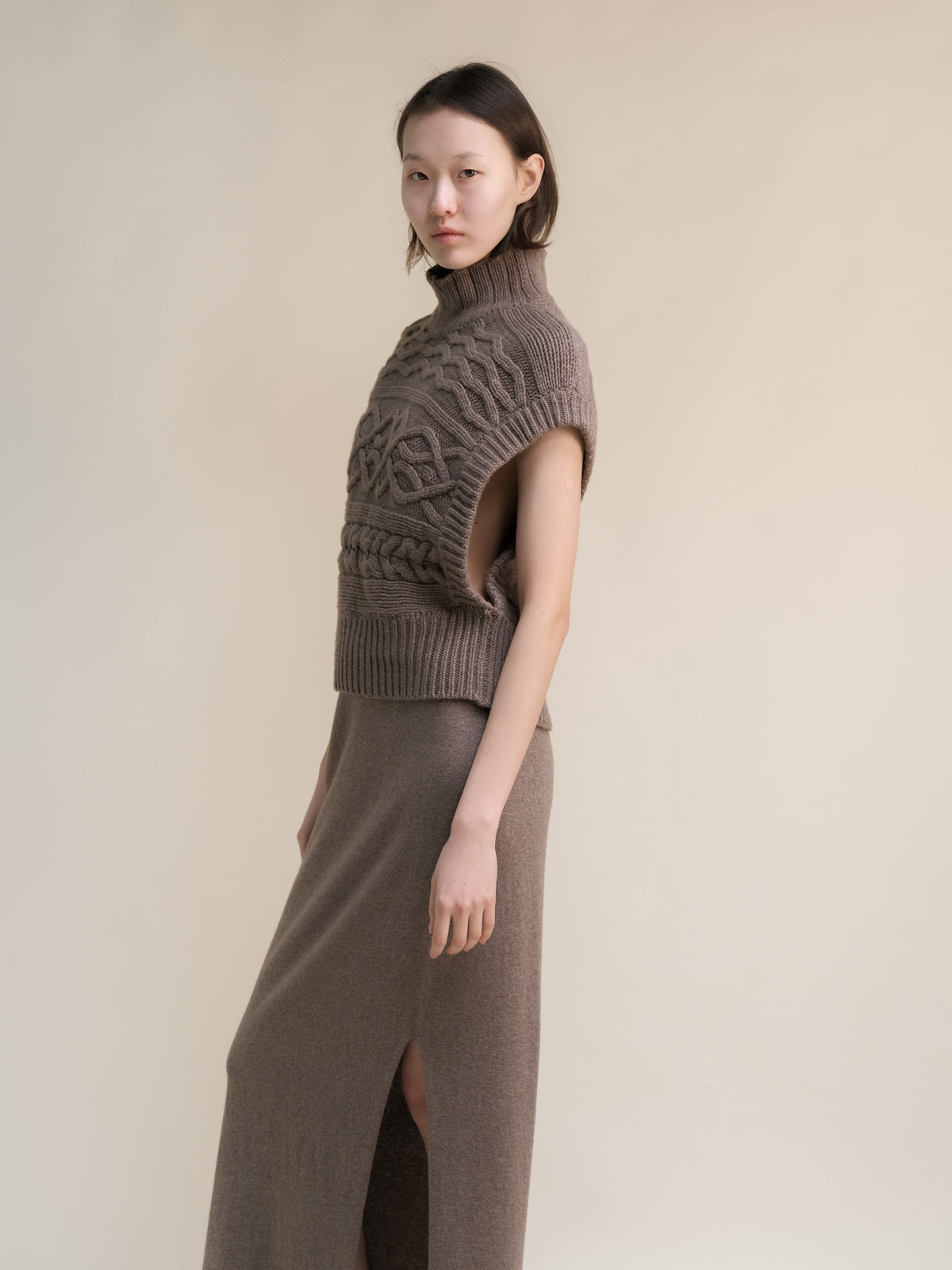 Taupe cashmere mix Maxi-Zopfstricktunika worn by a model with a hoher Kragen and sleeveless oversized armholes