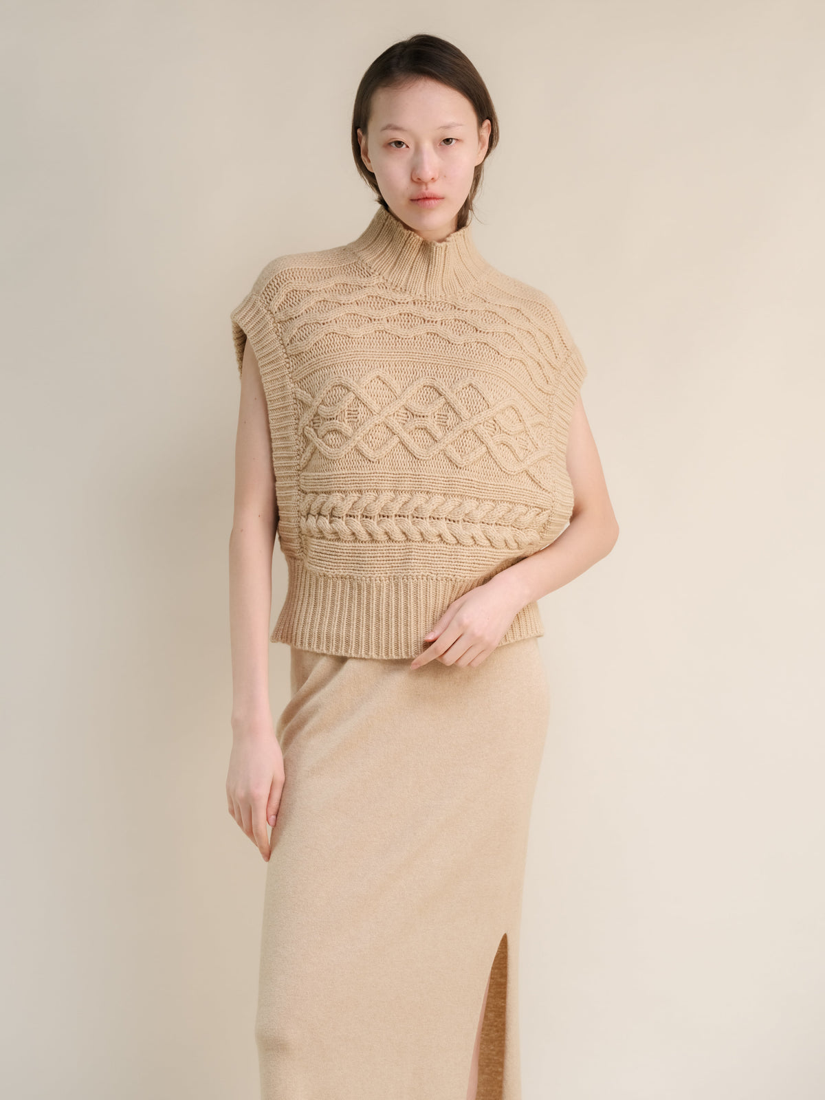 Beige sleeveless cashmere mix Maxi-Zopfstricktunika on a model with a chunky knit pattern and gerippter Saum.