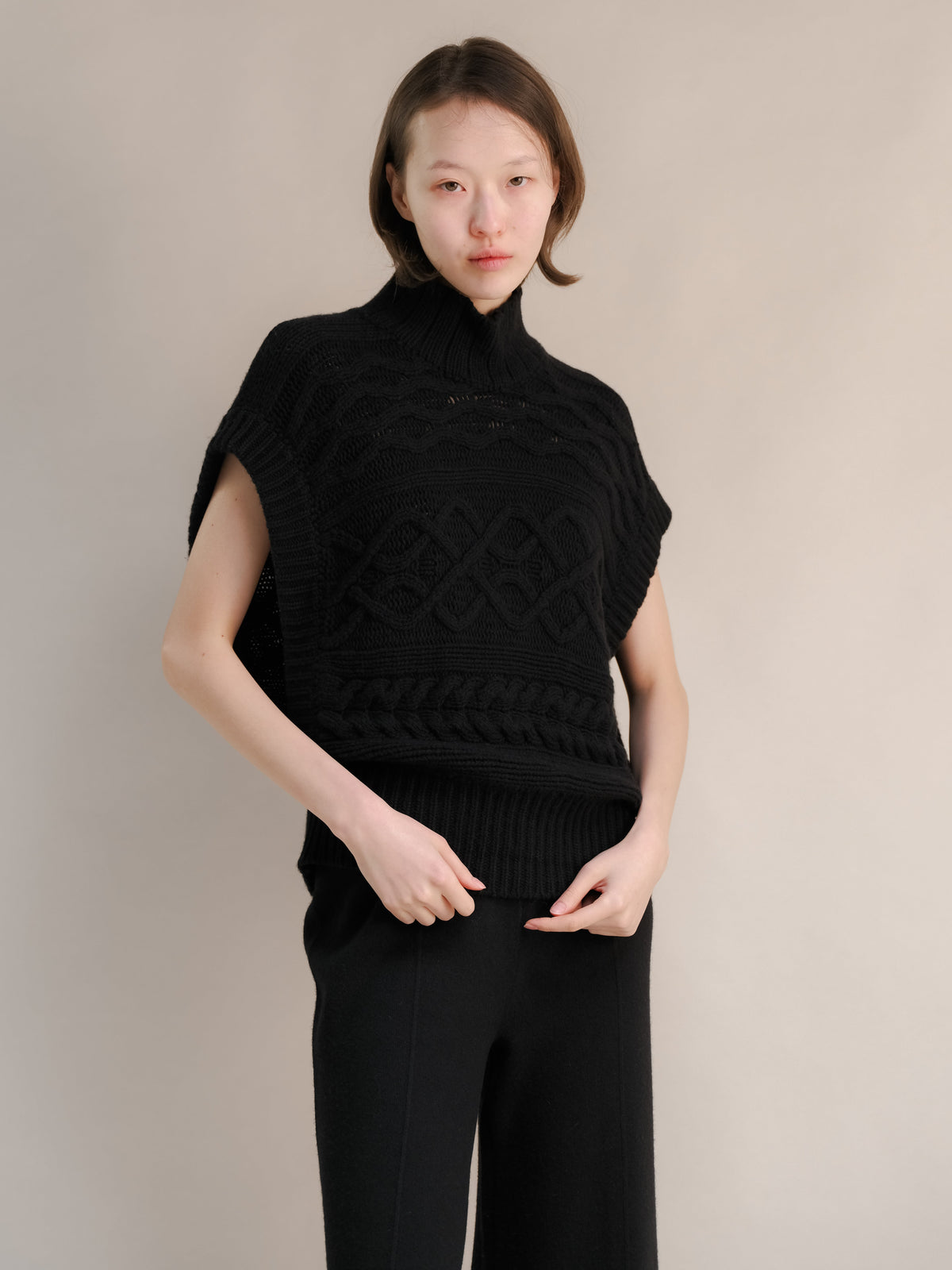 Model trägt a black cashmere mix Maxi-Zopfstricktunika with a snug hoher Kragen and chunky cable patterns.