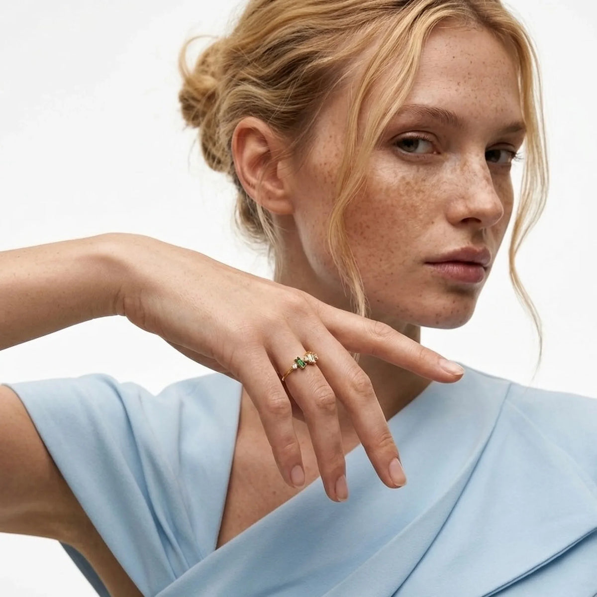 Frau trägt a gold ring on her finger against a neutral background