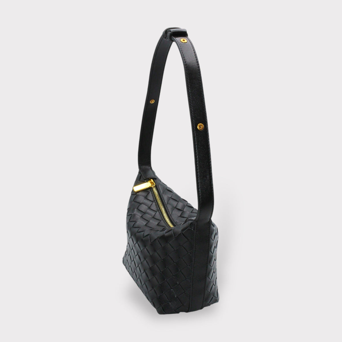 Side view of black woven leather box pouch with a long strap and finitions dorées