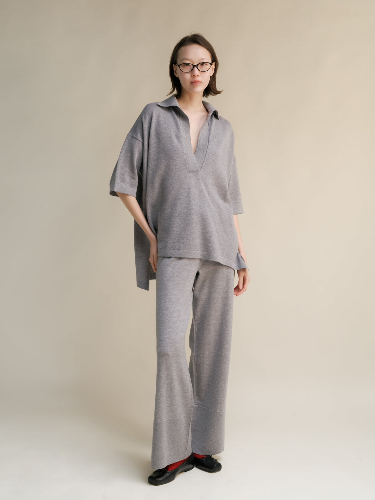 Modelo con grey oversized merino wool maxi polo with a collared neckline and pantalones de pierna ancha a juego.
