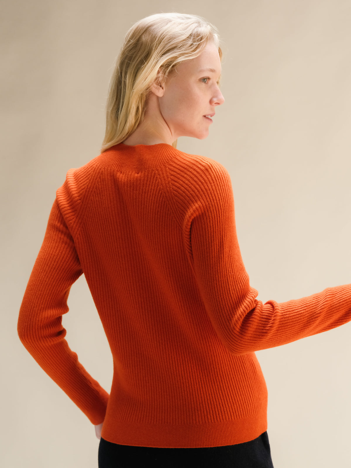 Achteraanzicht van een feloranje geribde mocknecktrui van kasjmiermix