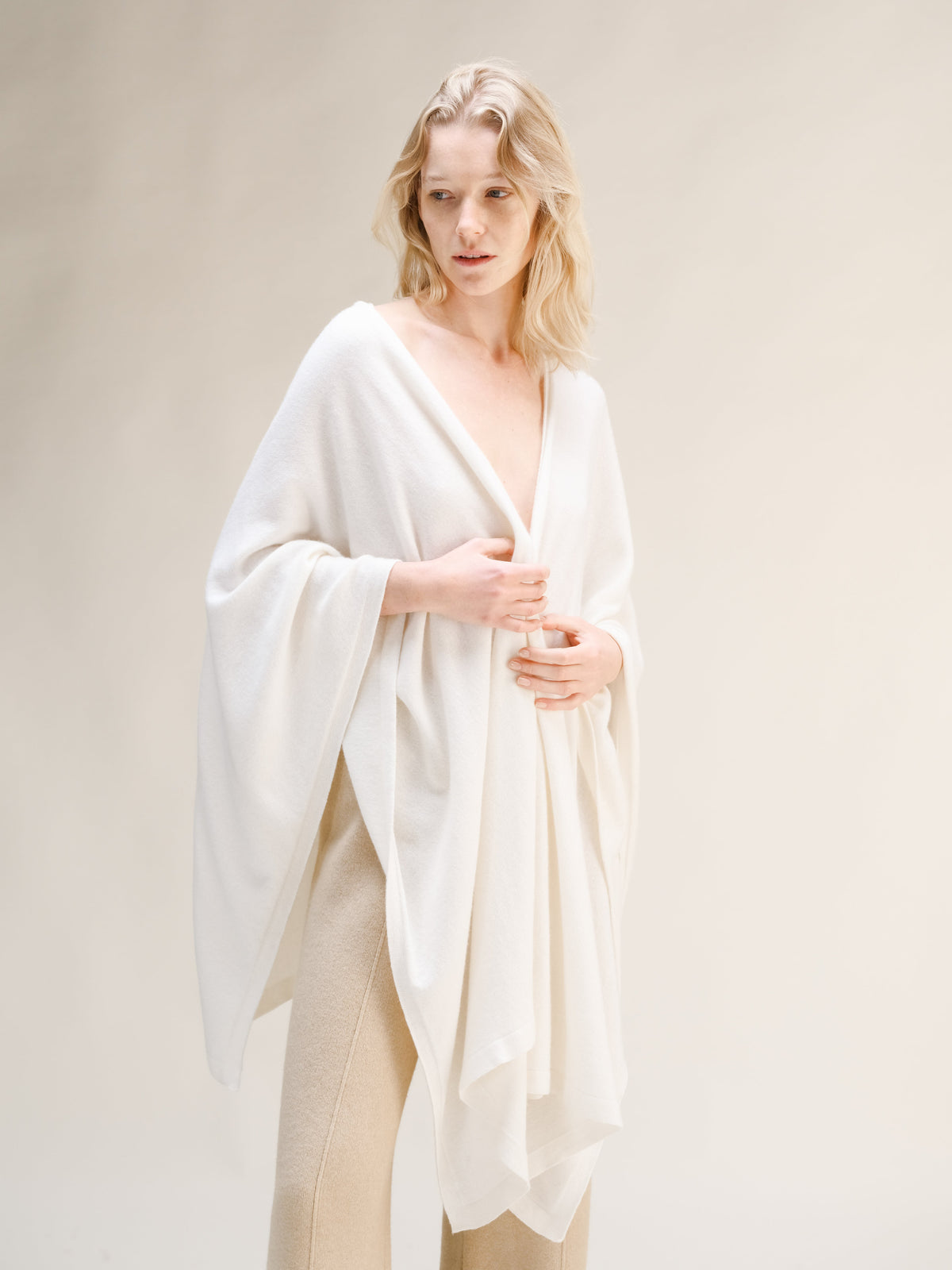 Modelo con capa maxi blanca de mezcla de cachemira sobre los hombros y pantalón de punto beige