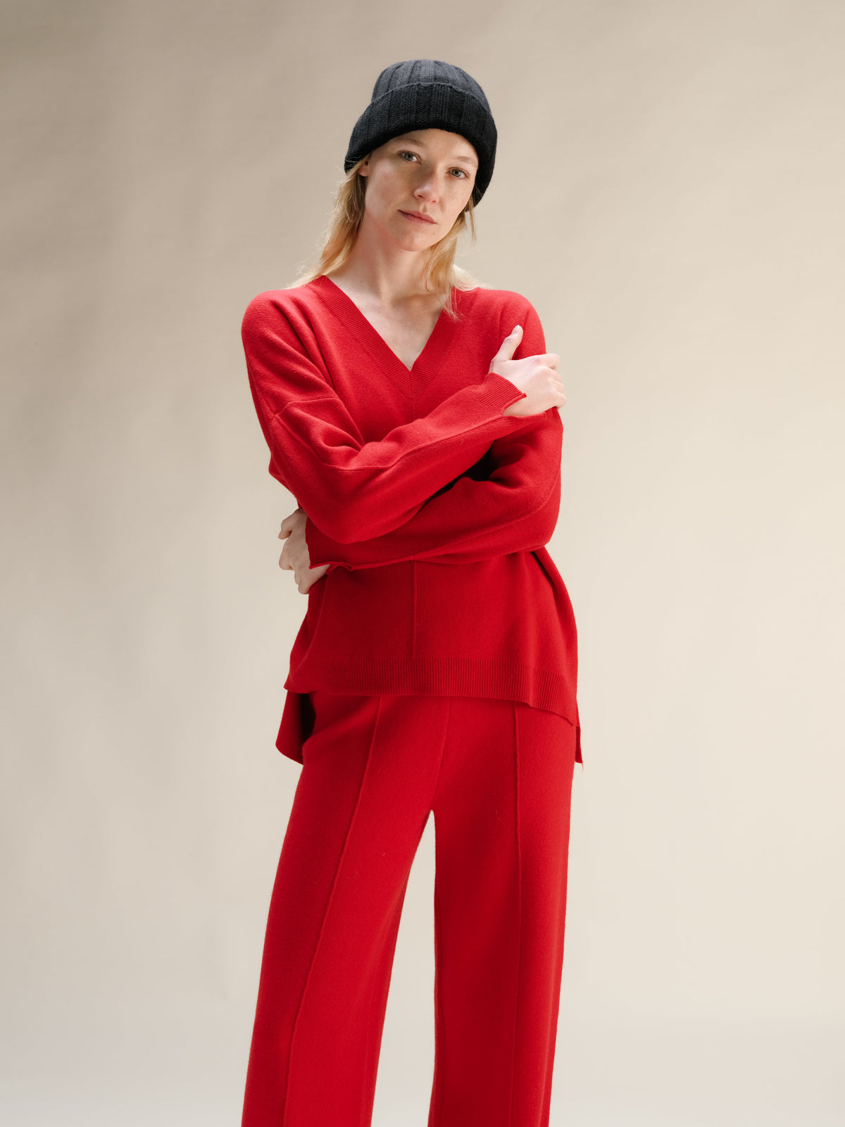 Personne en tenue rouge avec chapeau noir sur fond uni.