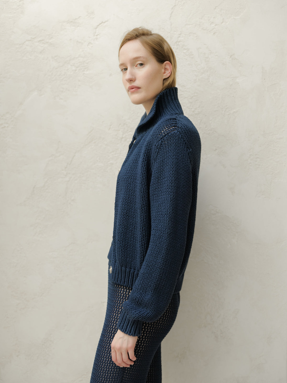 Side profile of a modella con a blu navy Fine Cotton Bomber Jacket con a chunky knit texture
