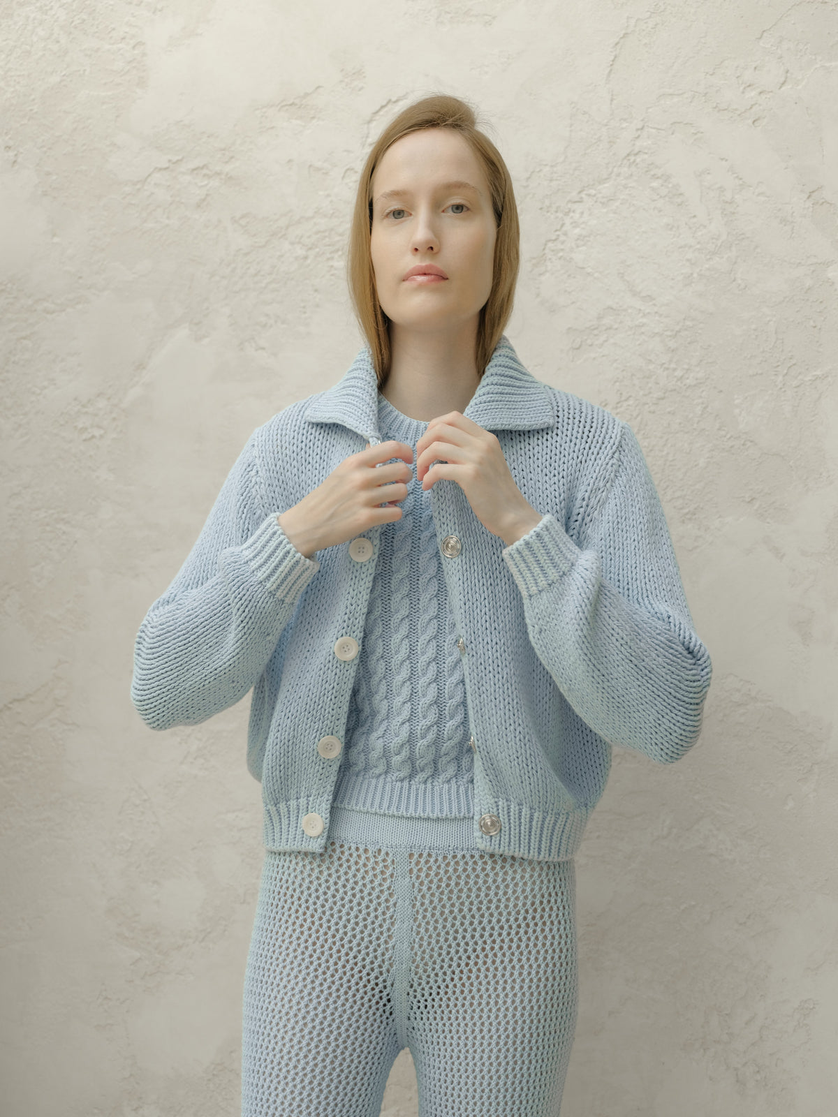 Vista frontale of azzurro pallido chunky knit bomber cardigan con large bianco buttons.