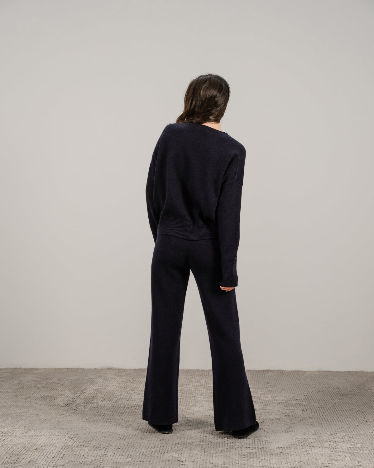 Back view of a model wearing navy cashmere mix crewneck sweater with matching wide-leg pants