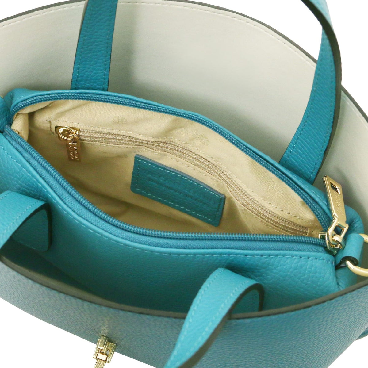 Top view of turquoise leather tote with beige fabric interior and zipped inner pocket featuring goudkleurige ritstrekker.