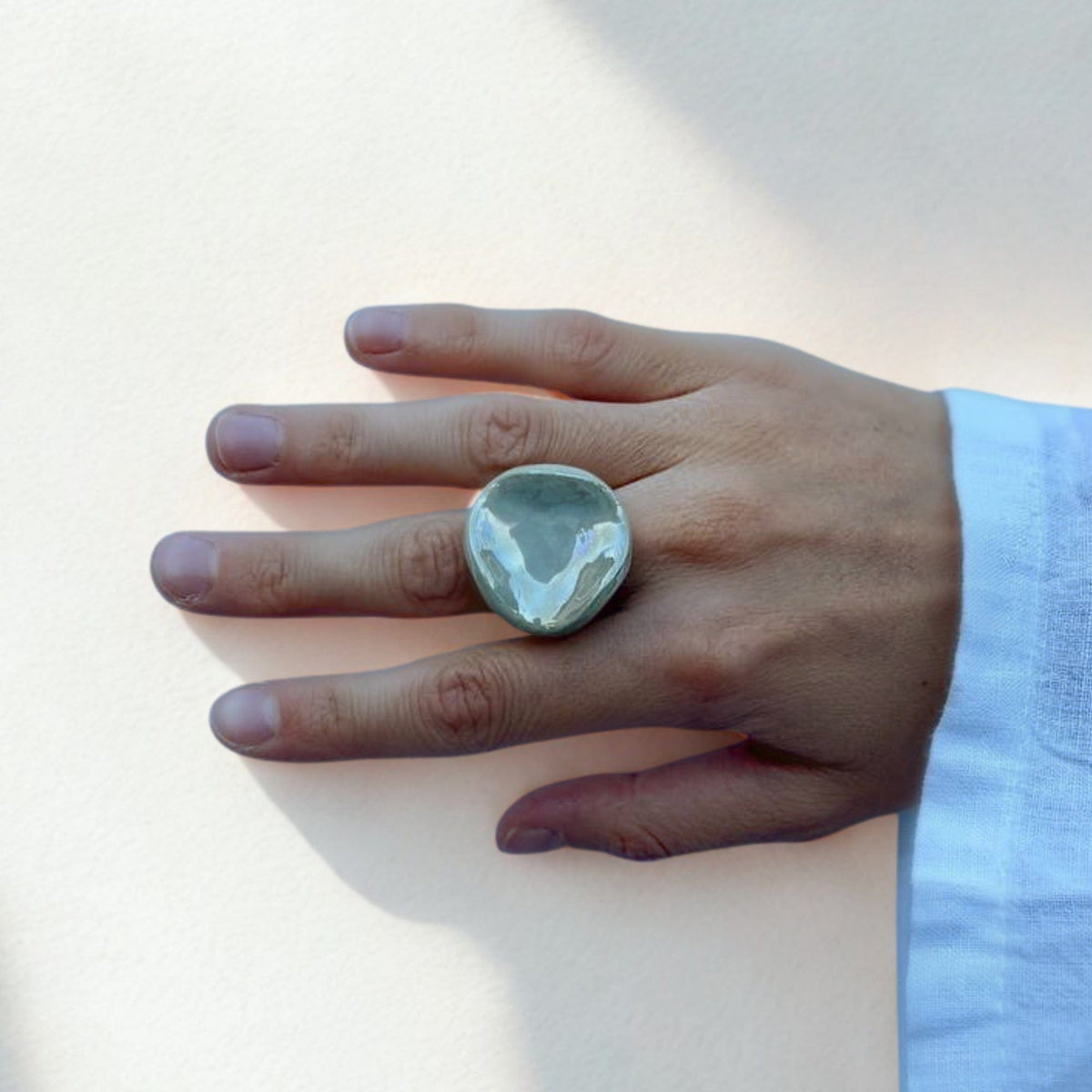 Anillo redondo de cerámica verde salvia en un dedo