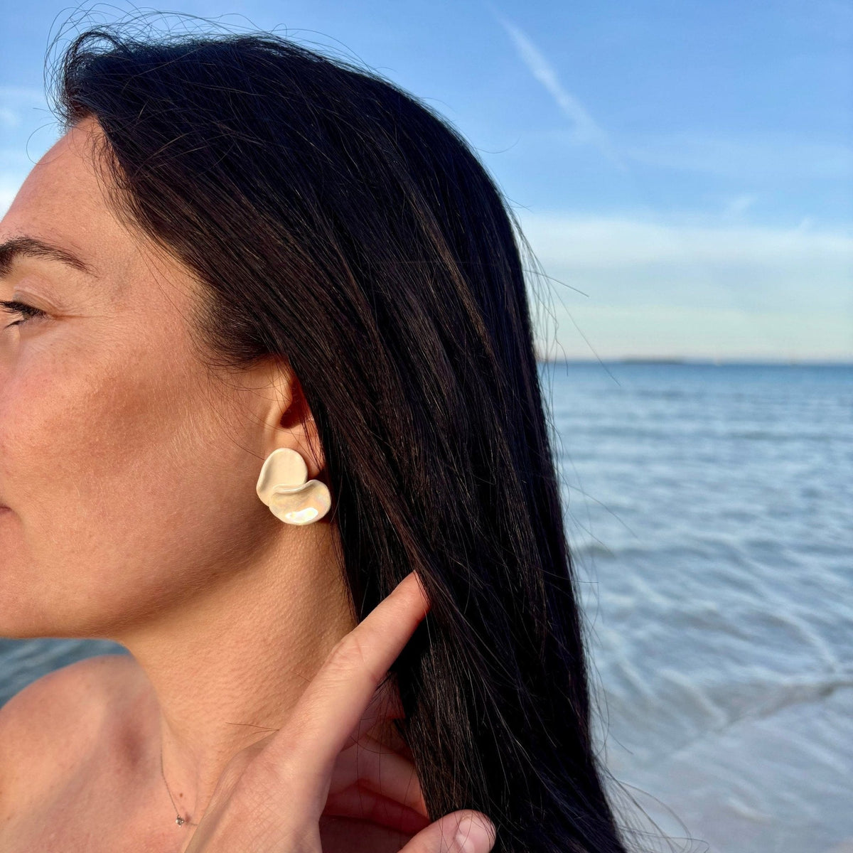 Petali pearl-white handcrafted ceramic stud earrings worn on the ear