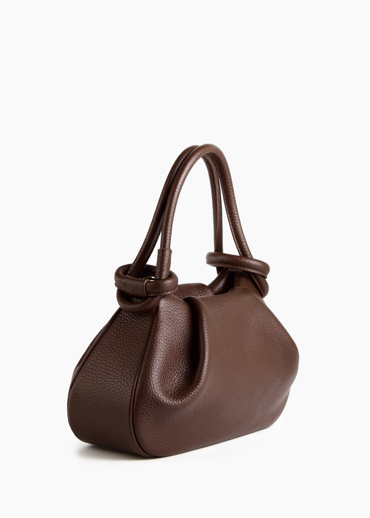 Bolso de piel granulada marrón oscuro con silueta fruncida y asas anudadas, visto en tres cuartos sobre fondo blanco.