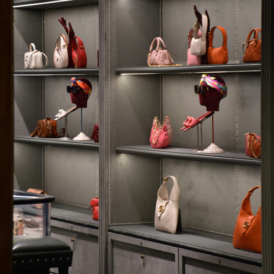 Boutique-Präsentation mit farbenfrohen Lederhandtaschen auf grauen Regalen.