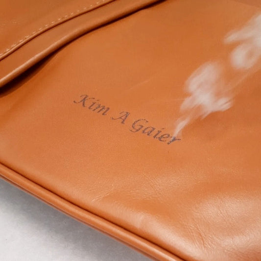 Lasergravur eines Namens auf eine karamellbraune italienische Lederhandtasche in der Tuscany-Leather-Manufaktur