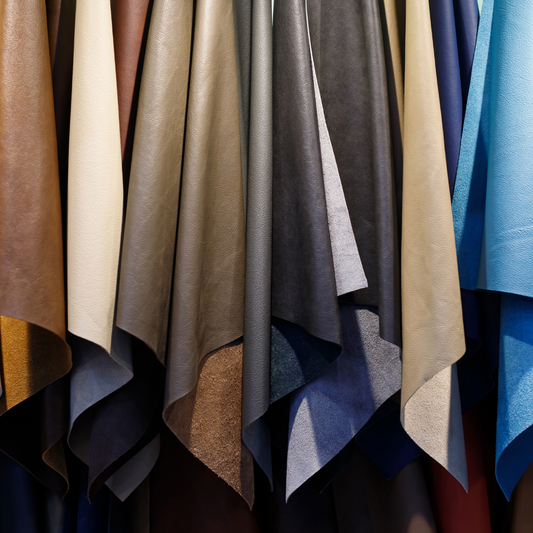 Diverse Italiaanse leervellen in warme neutrale tinten, hangend in een showroom.