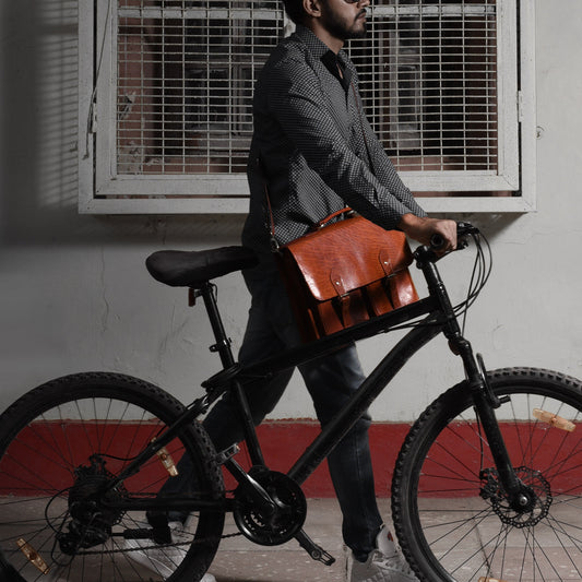 Man naast een zwarte fiets met een bruine leren messengertas over het frame.