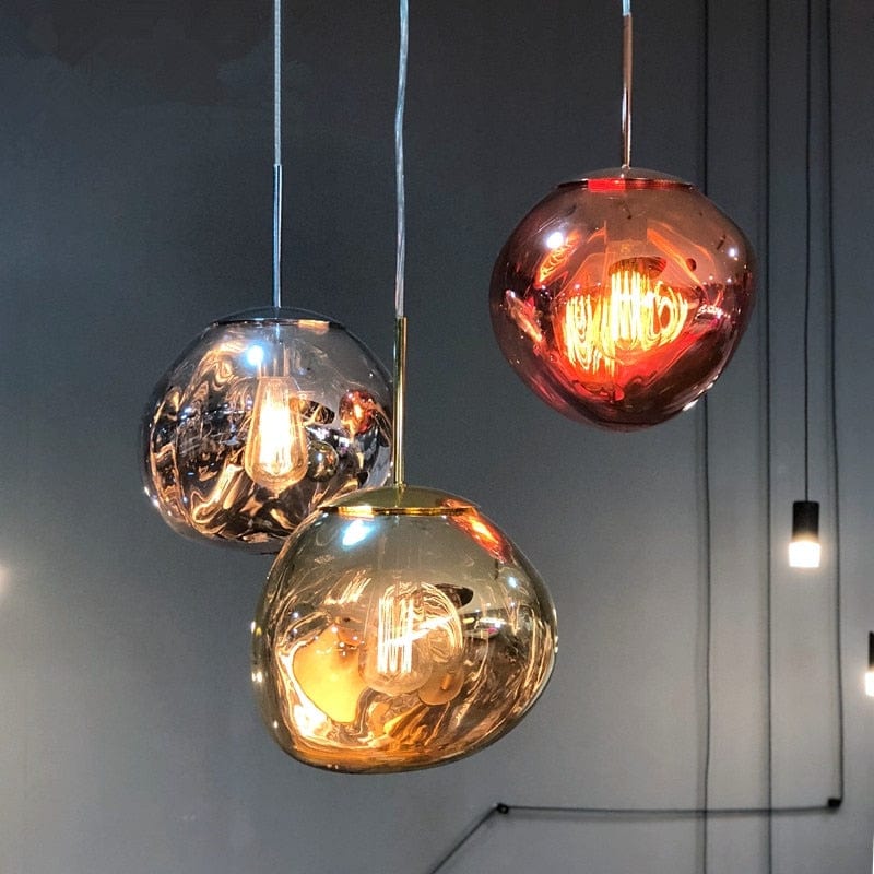 Trois suspensions en verre aux tons ambrés et transparents pendent du plafond d’une entrée moderne