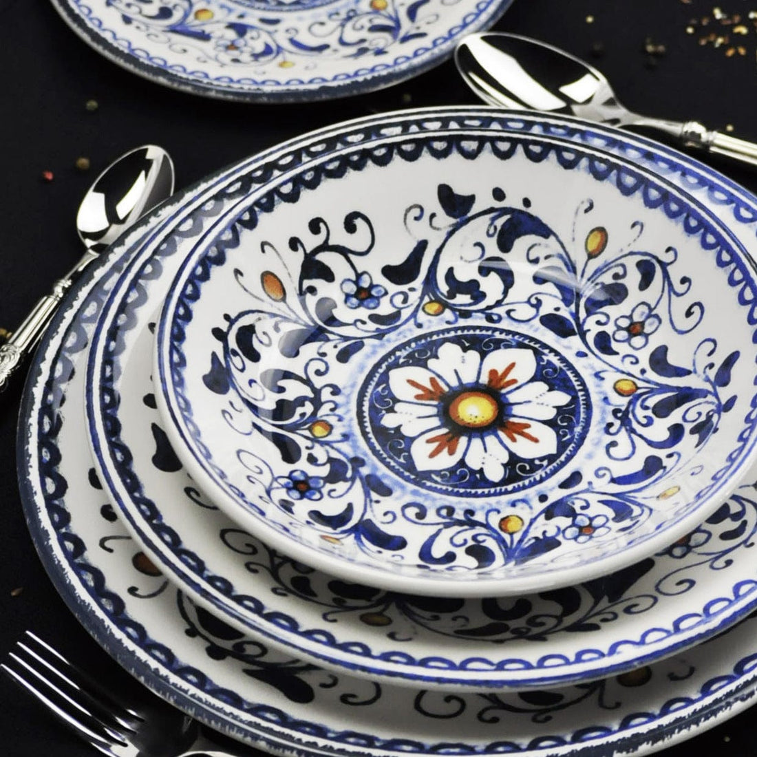 Nahaufnahme von blau-weissen Dekotellern mit Blumenmustern und Besteck auf einem dunklen Tisch