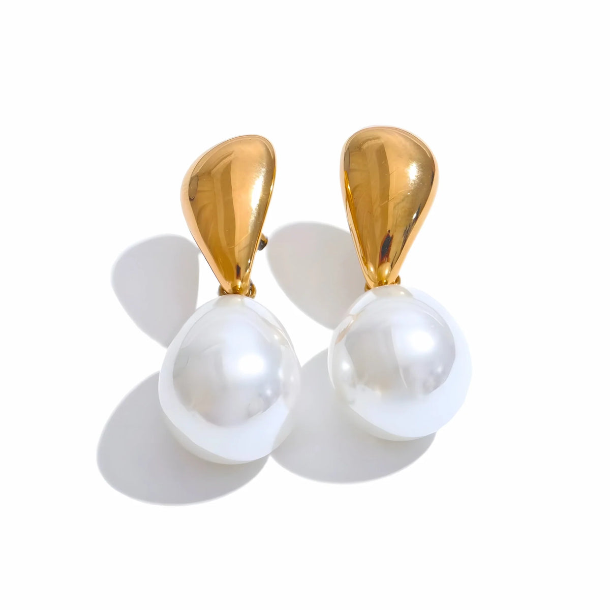 Pair of earrings with gold tops and white pearls vor weissem Hintergrund
