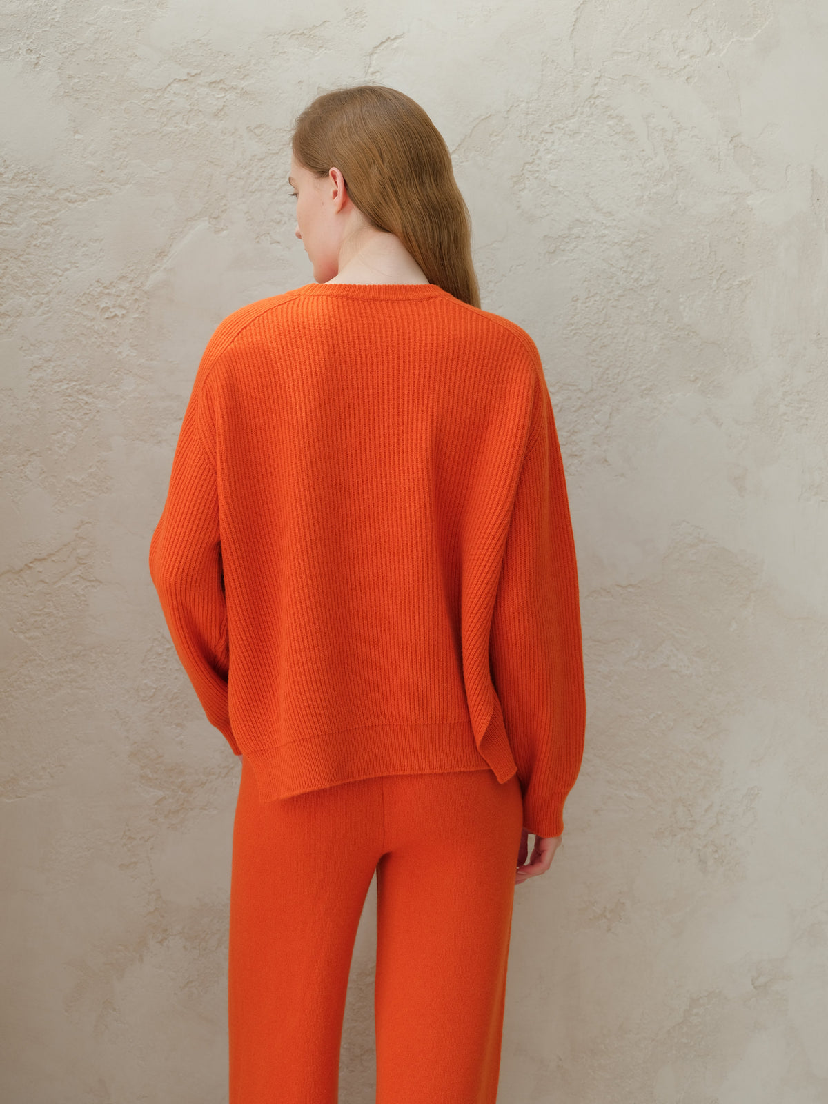 Back view of a modelo con an orange cashmere mix crewneck ribbed sweater