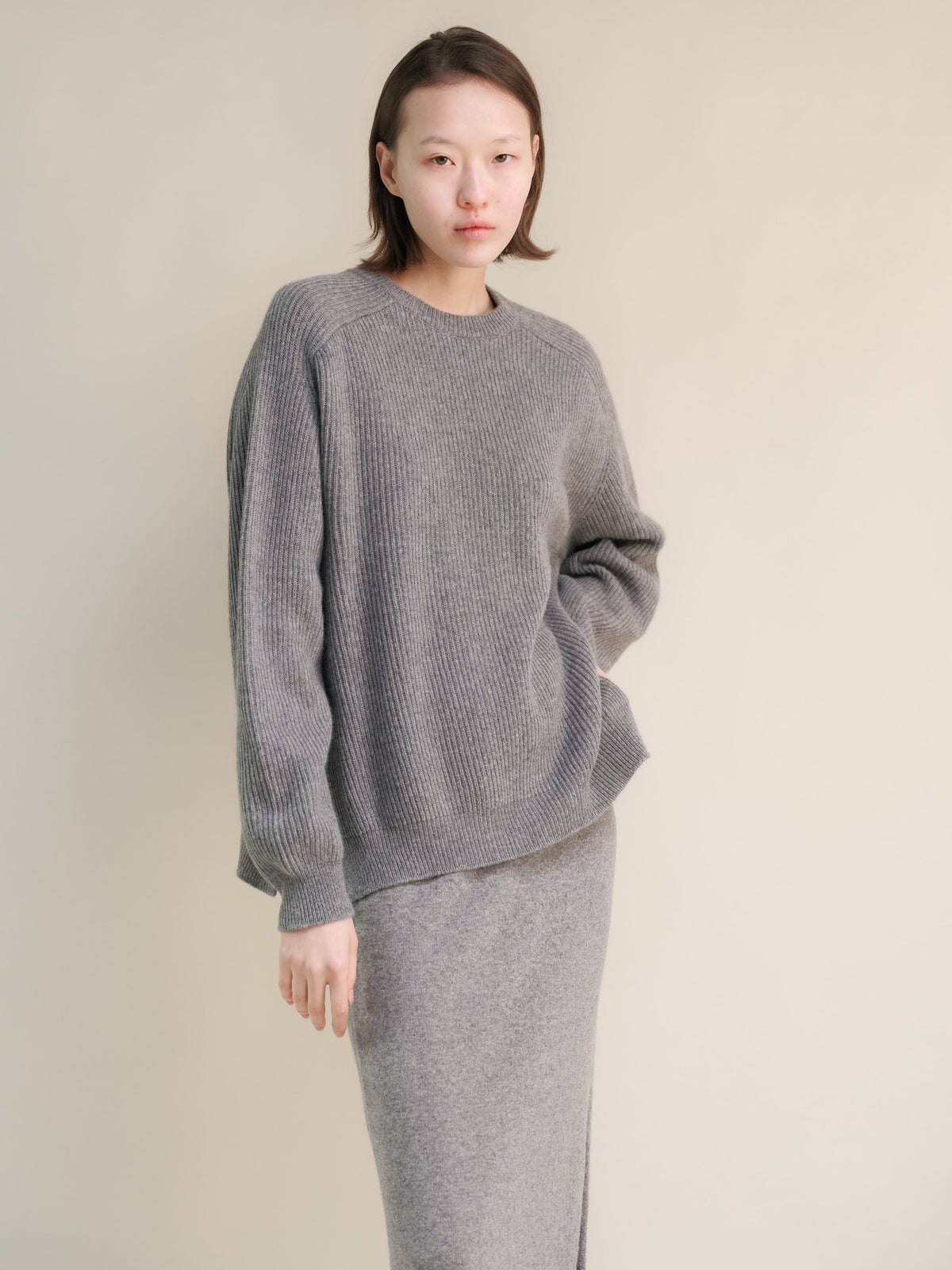 Modelo con gray ribbed cashmere mix jersey de cuello redondo with corte relajado and a matching knit skirt.