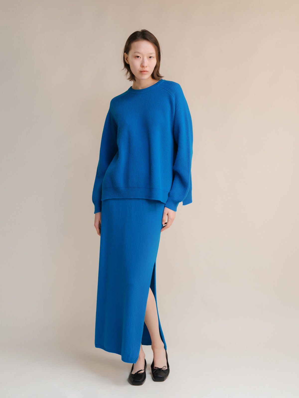 Modelo con a bright blue cashmere mix crewneck ribbed sweater with a matching blue maxi skirt in a studio