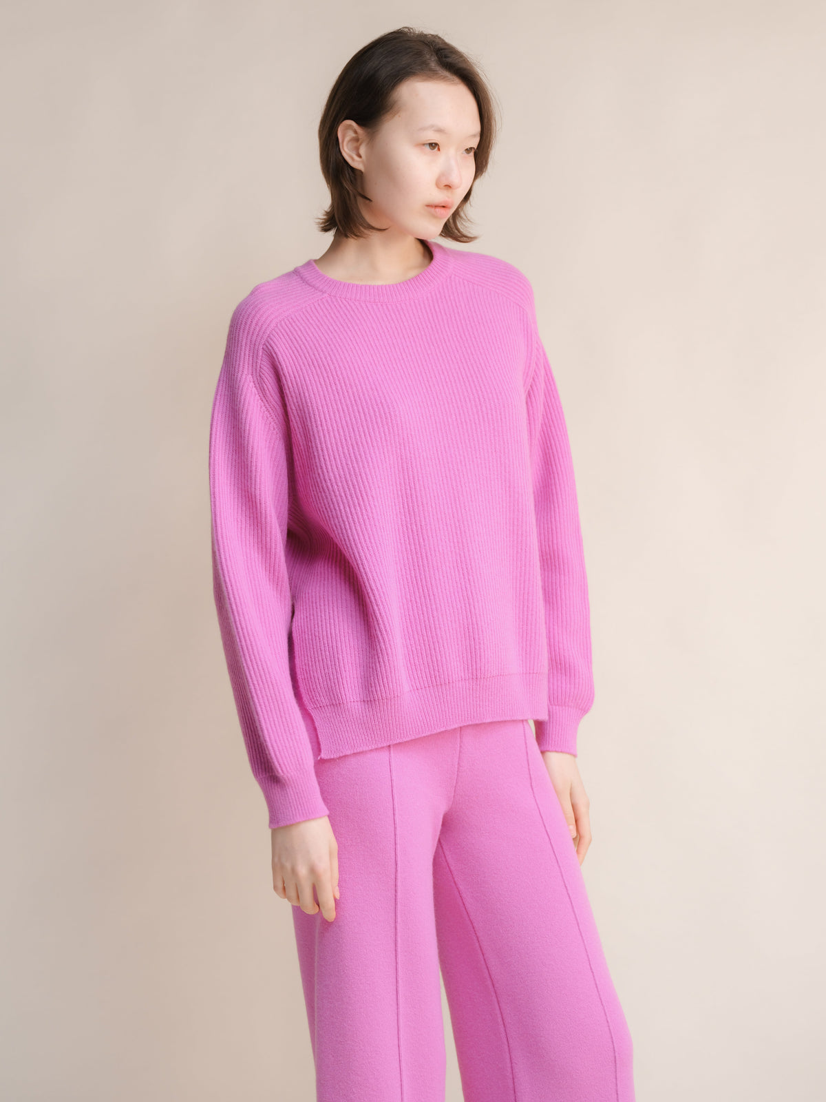 Modelo con a pink cashmere mix crewneck ribbed sweater with side slits and matching pink pants