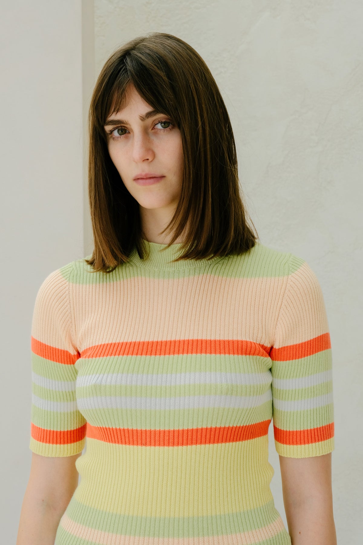 Mujer con a colorful striped sweater against a plain background