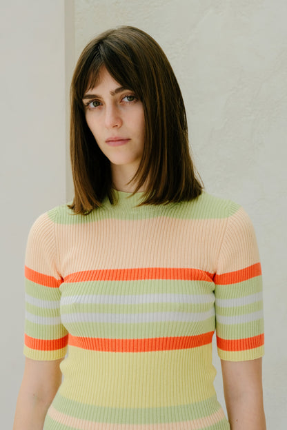 Mujer con a colorful striped sweater against a plain background