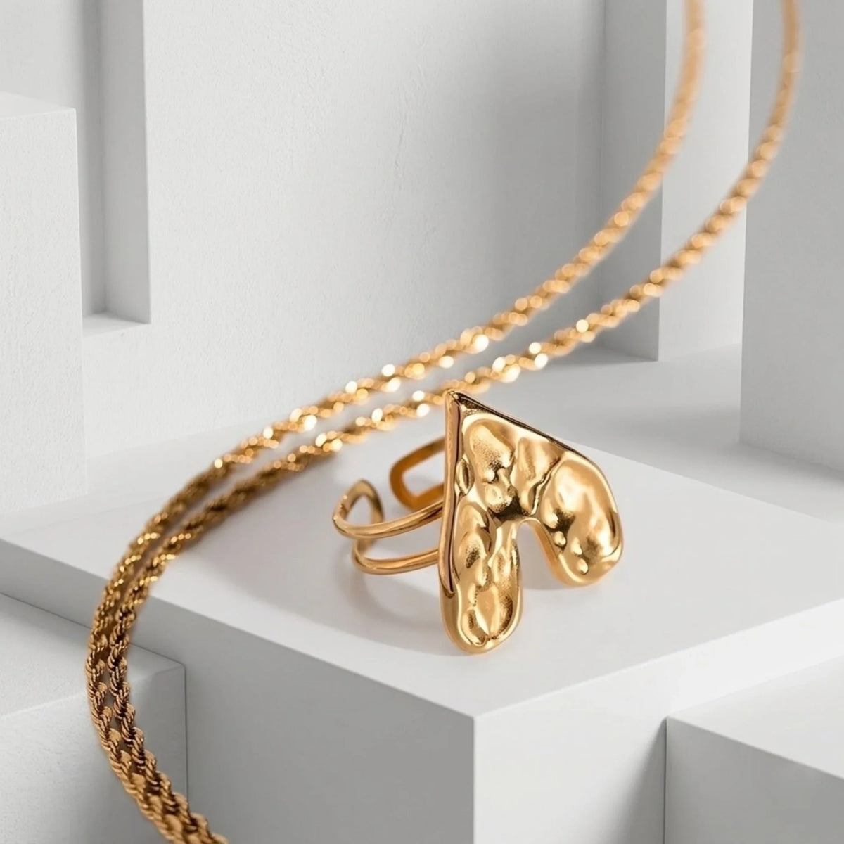 Gold necklace with a unique heart ring on a white background