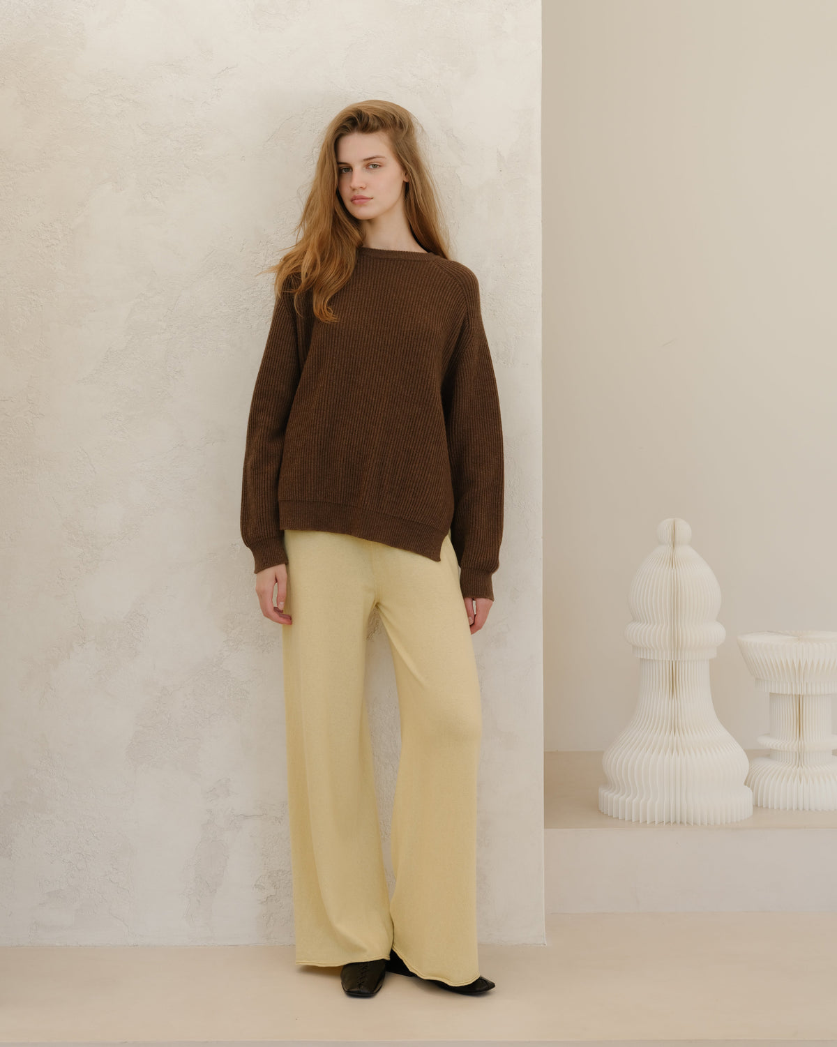 Modelo con brown ribbed cashmere mix jersey de cuello redondo with lateral slits, paired with pale beige pantalones de pierna ancha
