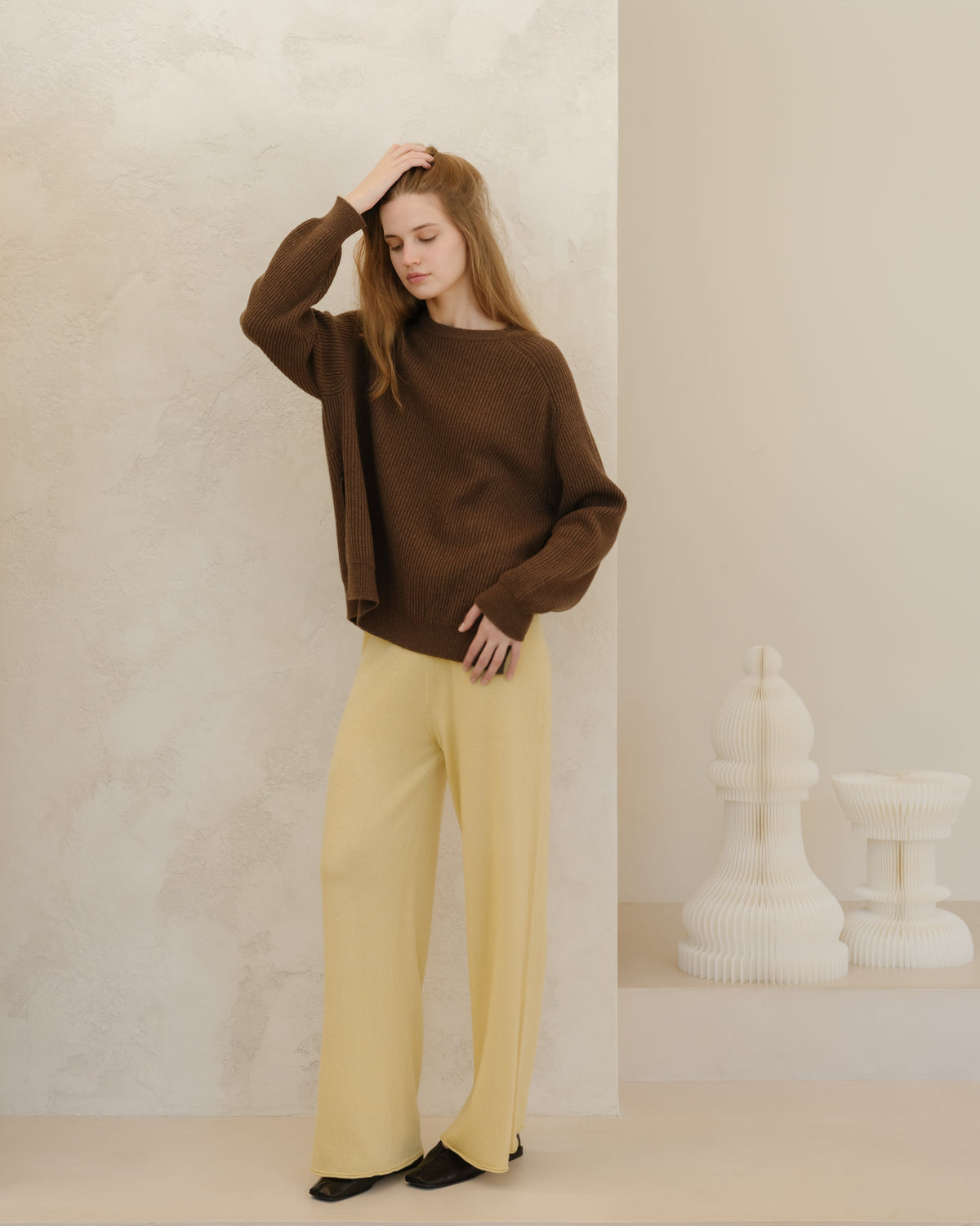 Modelo con a brown ribbed cashmere mix jersey de cuello redondo with side slits and pale yellow pantalones de pierna ancha.