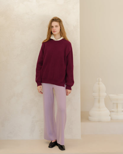 Modelo con burgundy oversized ribbed cashmere mix sweater with a white collared shirt peeking out and lavender trousers.