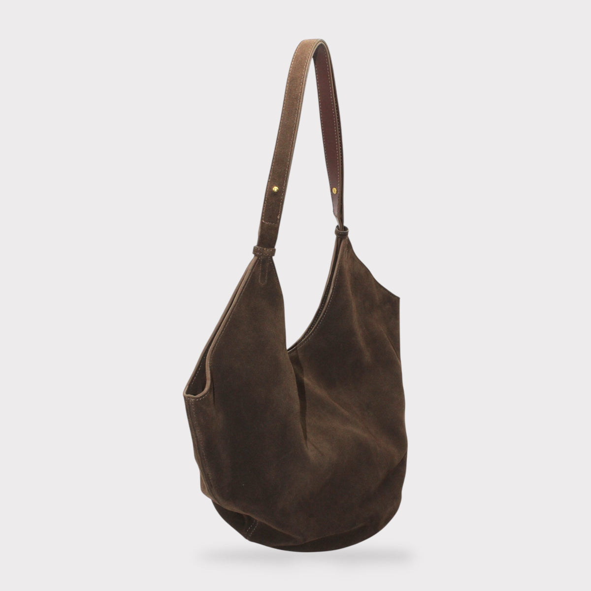 Elsa suede leather boat tote with circular leather base and long verstelbare riem tegen witte achtergrond.