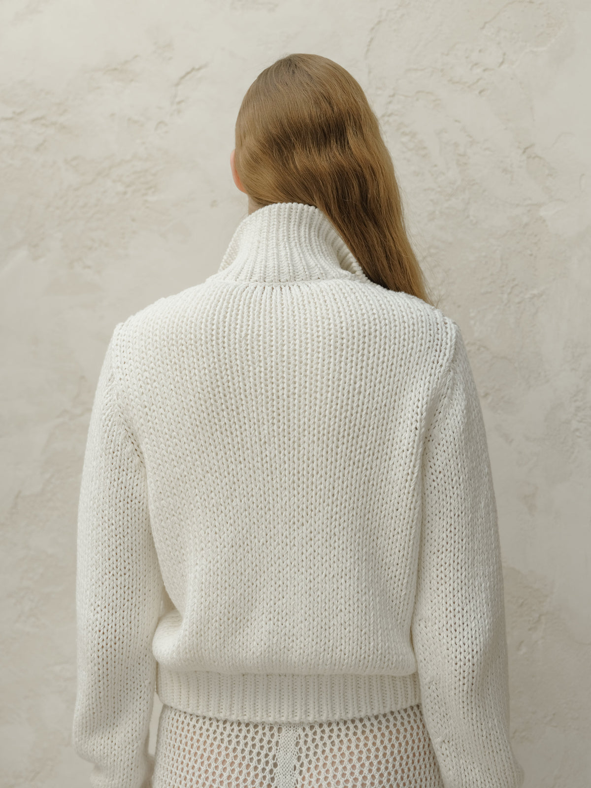 Back view of bianco chunky knit bomber jacket con a tall ribbed collar.