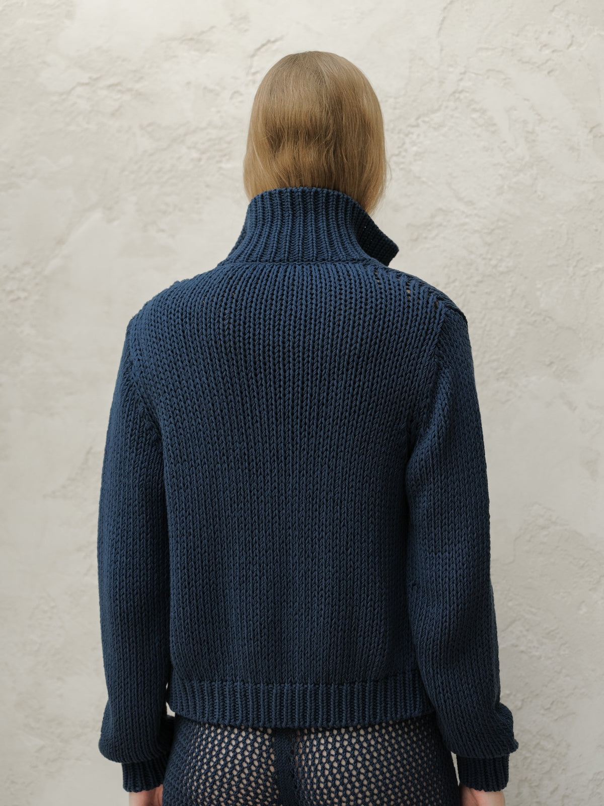 Back view of a model in a blu navy Fine Cotton Bomber Jacket con a tall ribbed collar