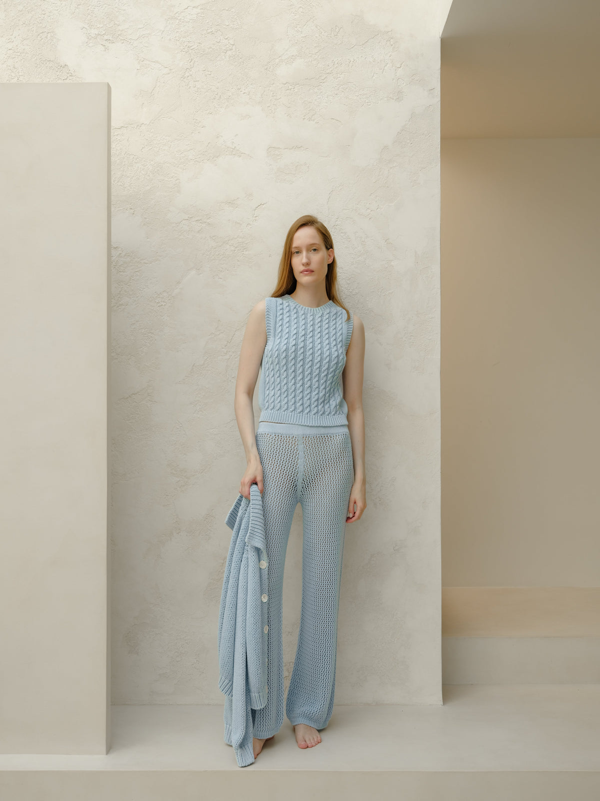 Modella con azzurro pallido top in maglia senza maniche con matching wide leg knit pants holding a cardigan