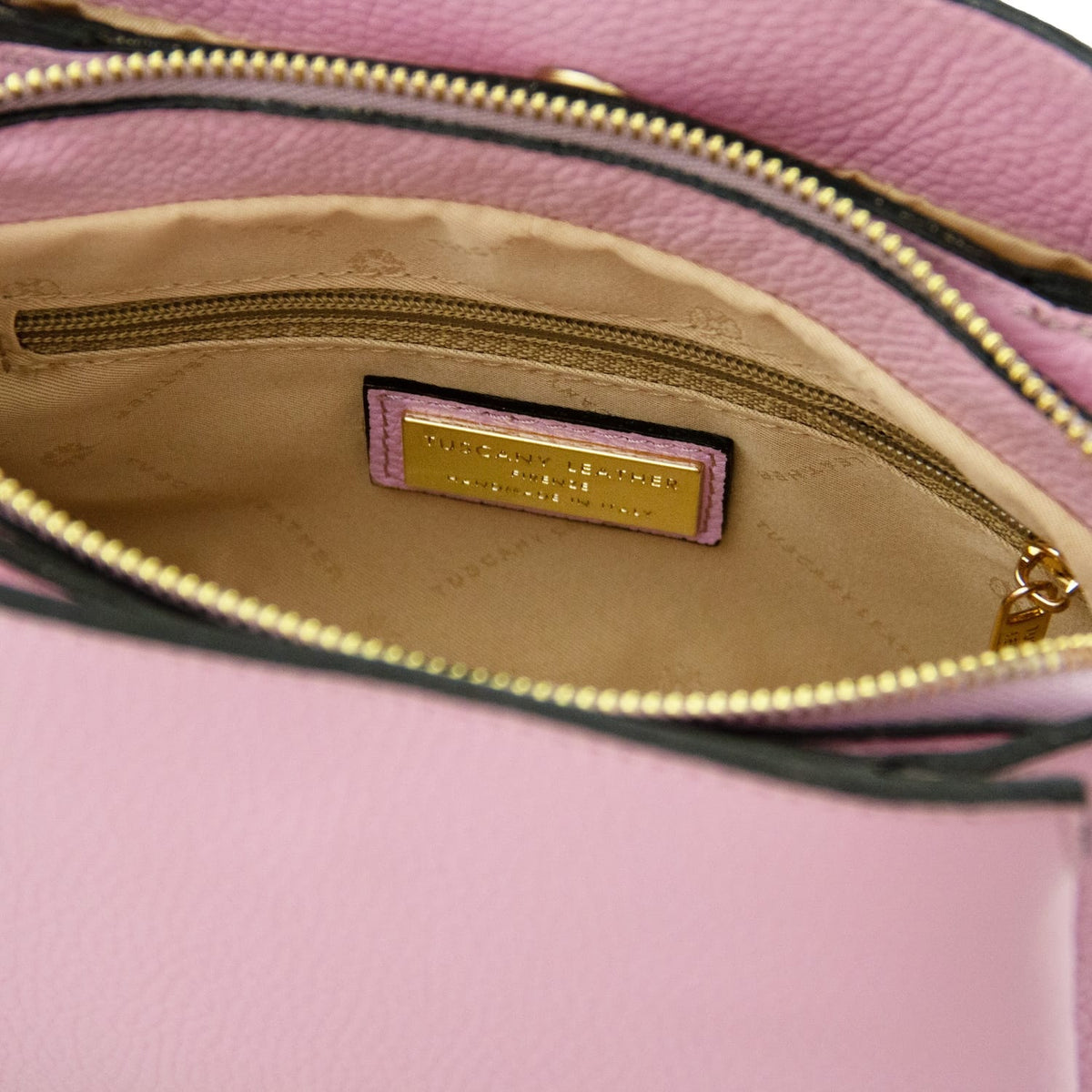 Innenansicht of Abby pink leather shoulder bag zeigt beiges Futter, Reissverschlusstasche and brand plaque.