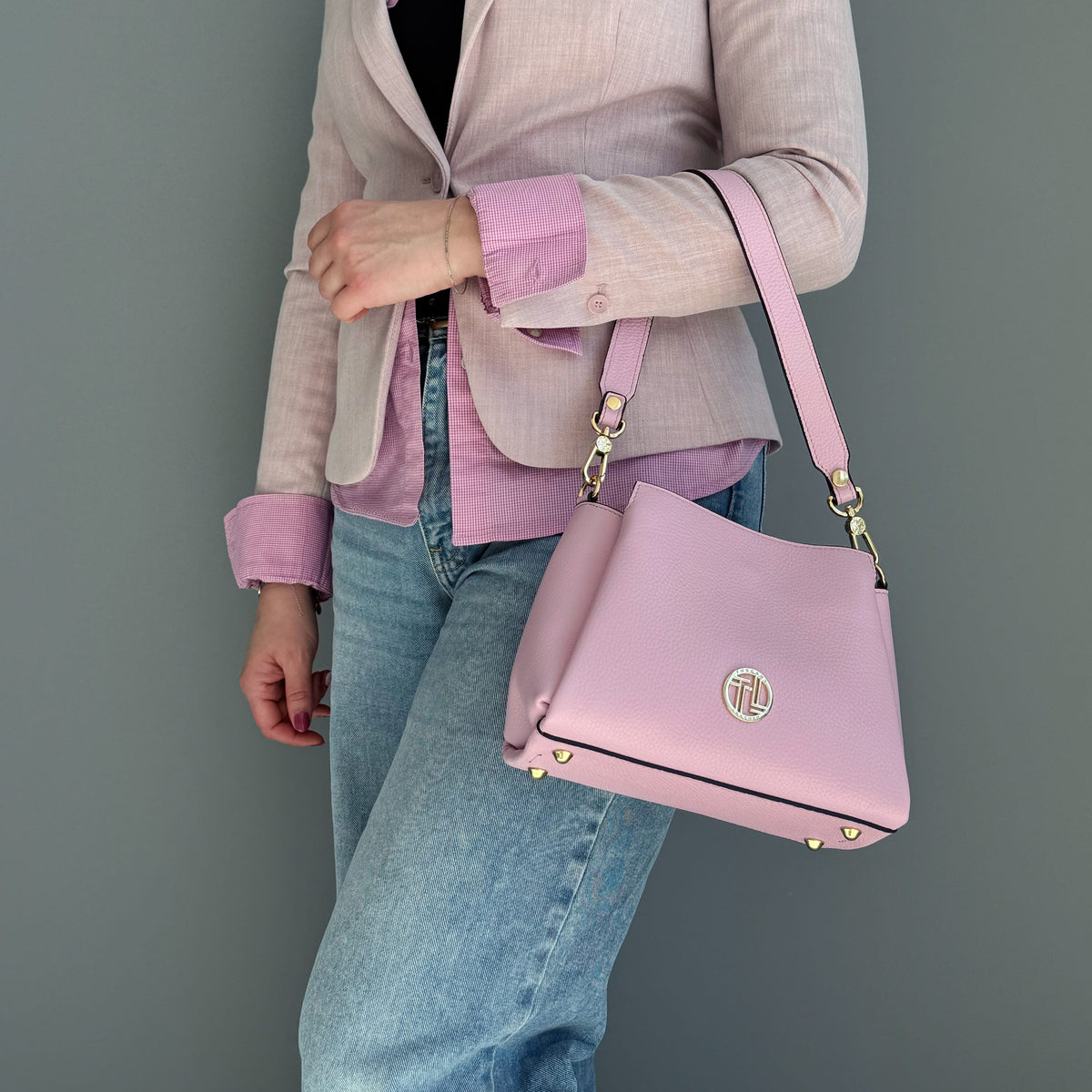 Rosa Abby leather shoulder bag carried by Model trägt a pink blazer and jeans.