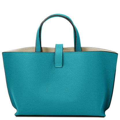 Turquoise full-grain leather tote purse with simple strap closure and smooth natural interior lining.