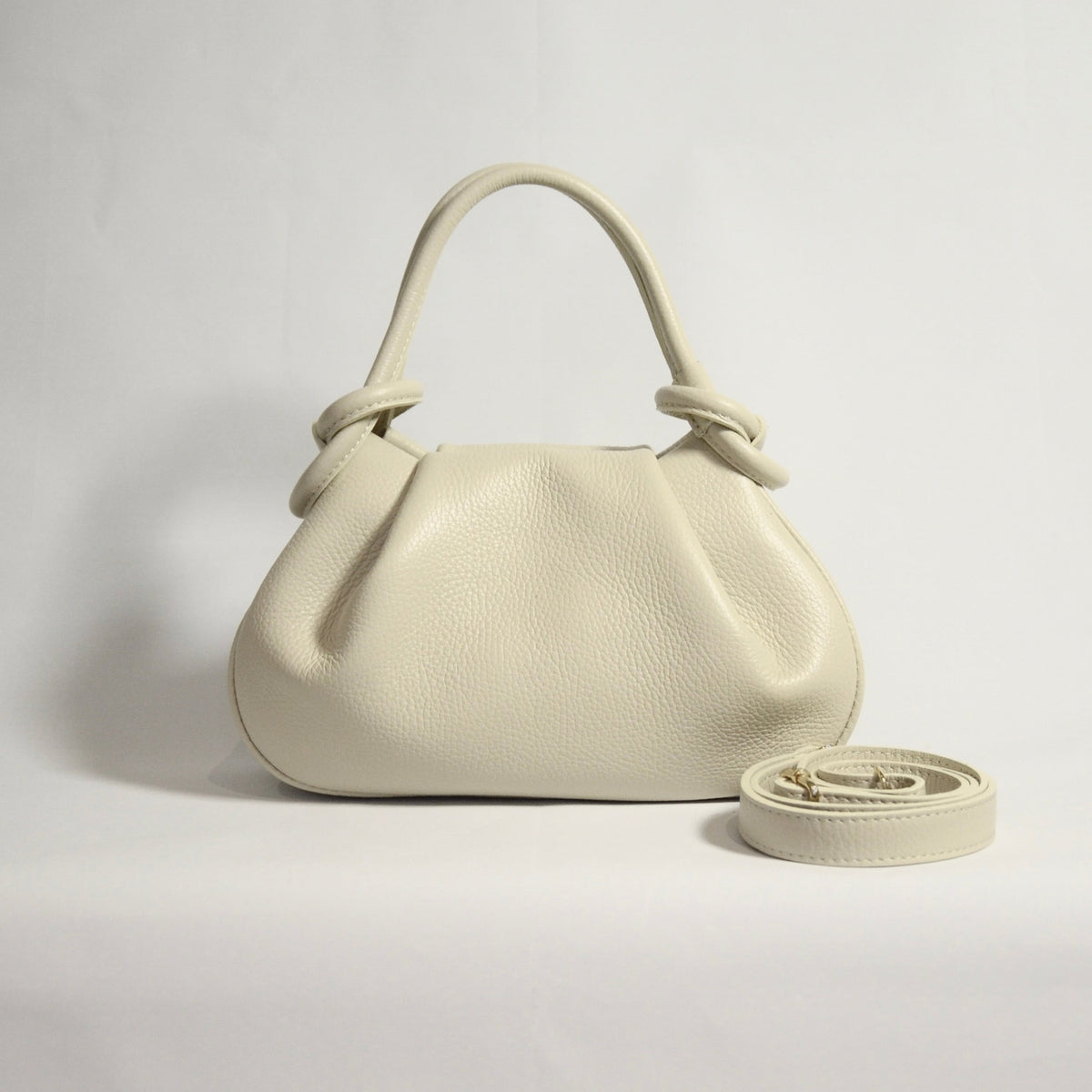 Beige handbag with matching strap on a light gray background