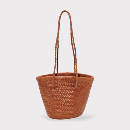 Carmel hand woven brown leather shoulder bucket bag with braided handles on a clean white background.