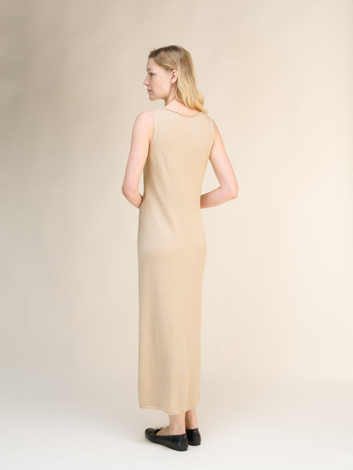 Back view of beige cashmere blend boat neck sleeveless dress on a model con a spacco laterale