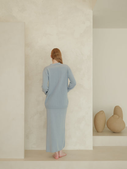 Back view of model wearing pale blue 3D knit cashmere blend cardigan over a matching long skirt