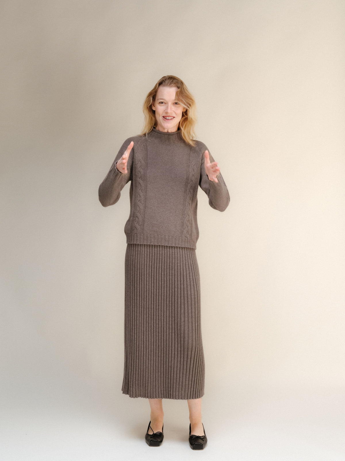 Model wearing a taupe cashmere blend knit sweater and matching long ribbed skirt.