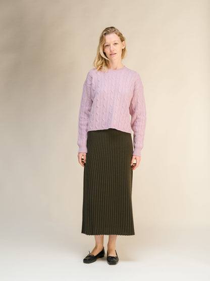 Model wearing a pink cable knit sweater with a dark olive ribbed midi skirt from the cashmere blend 3D knit collection